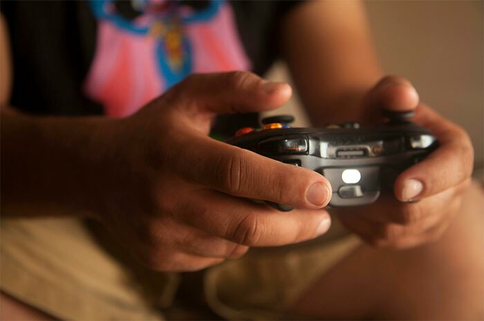 Close-up of a person holding a game controller, illustrating frustration with over-the-top workplace rules and policies.