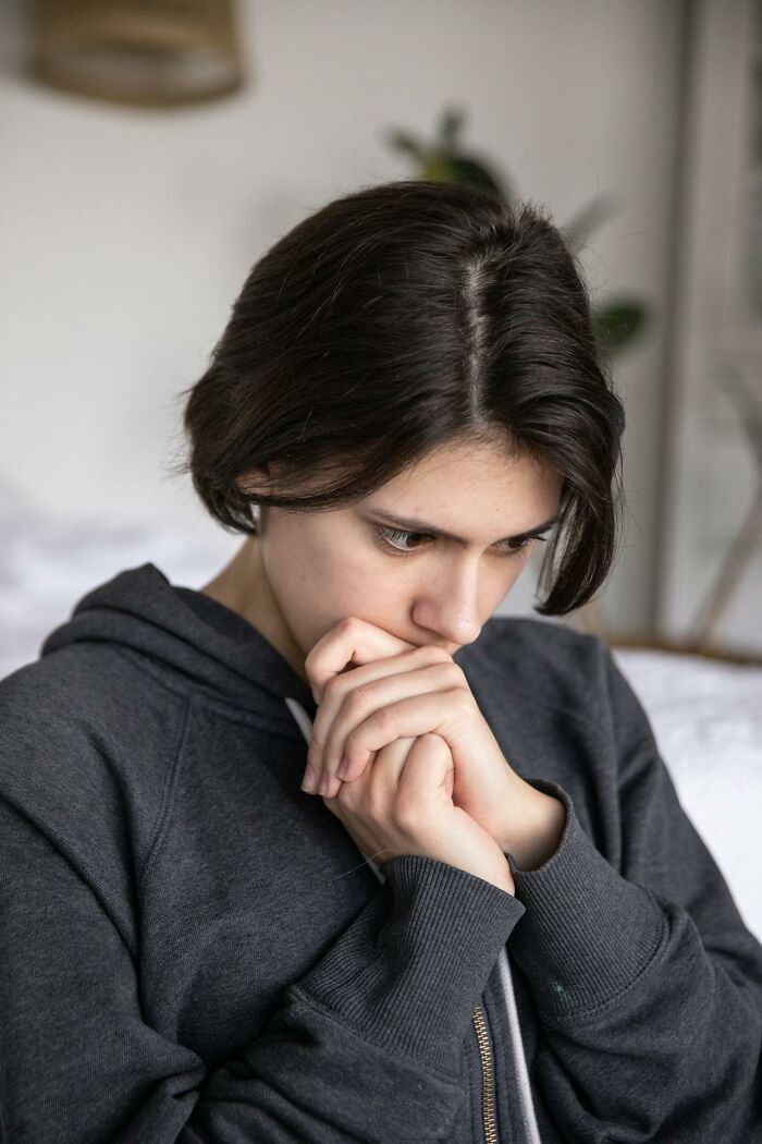 Young person in a dark hoodie looking worried and thoughtful, symbolizing first signs someone is having an affair.