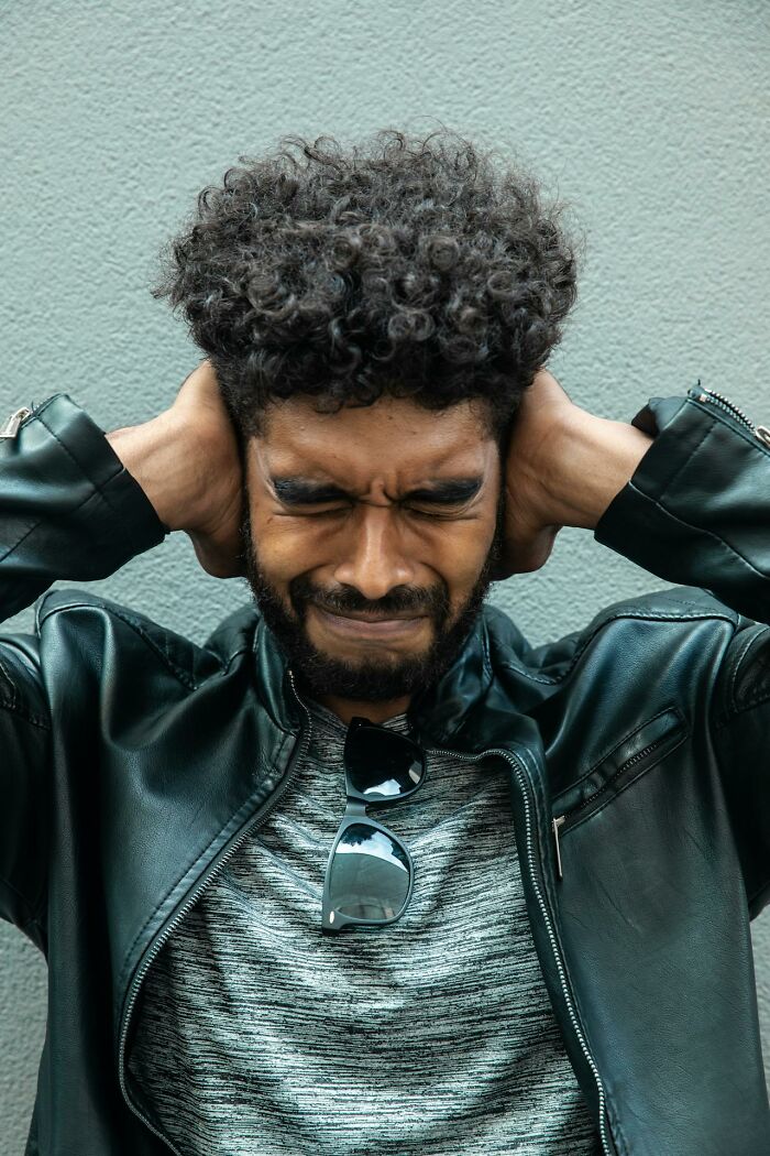 Man with curly hair and leather jacket appearing stressed, illustrating secrets people are hiding from their partners.