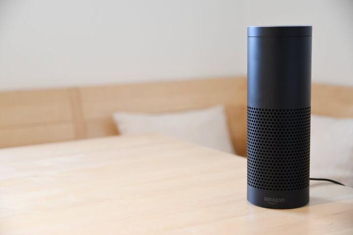 Black Amazon Echo smart speaker on light wooden table in a minimalistic room, illustrating subtle sexist design issues for men.