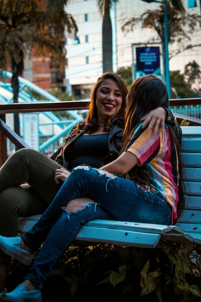Two women sitting on a bench outdoors, one smiling, illustrating how spouses changed after the wedding and ignored red flags.