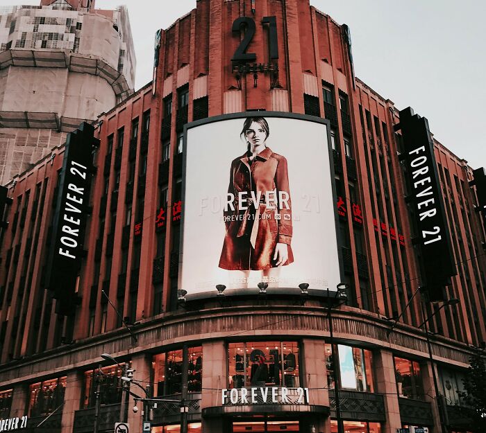 Outdoor Forever 21 brand billboard on a city building featuring a fashion model in a red coat.
