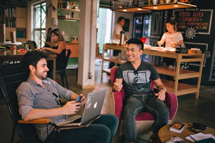 Two men chatting and smiling in a cozy cafe, illustrating secrets people are hiding from their partners.