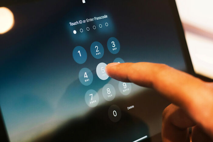 Close-up of a person entering a passcode on a touchscreen device illustrating stalking and security concepts.