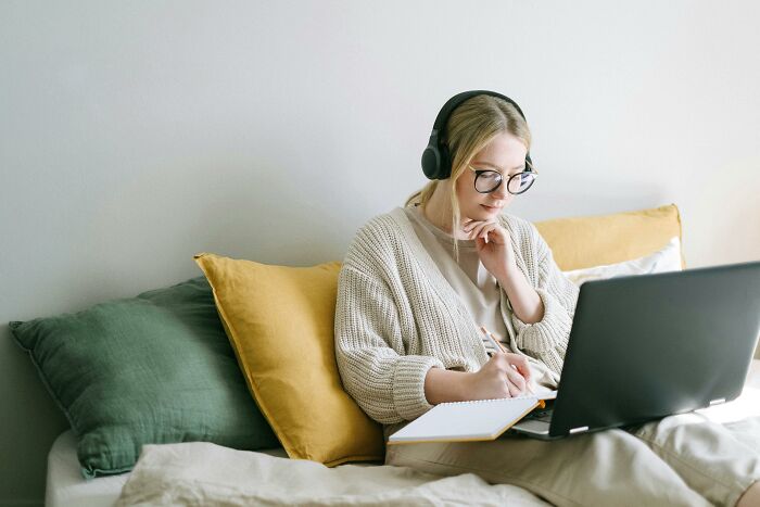 Young woman with glasses and headphones taking an online 50-50 quiz testing the sharpest minds scoring above 26/35. Young woman with glasses and headphones taking an online 50-50 quiz testing the sharpest minds scoring above 26/35.