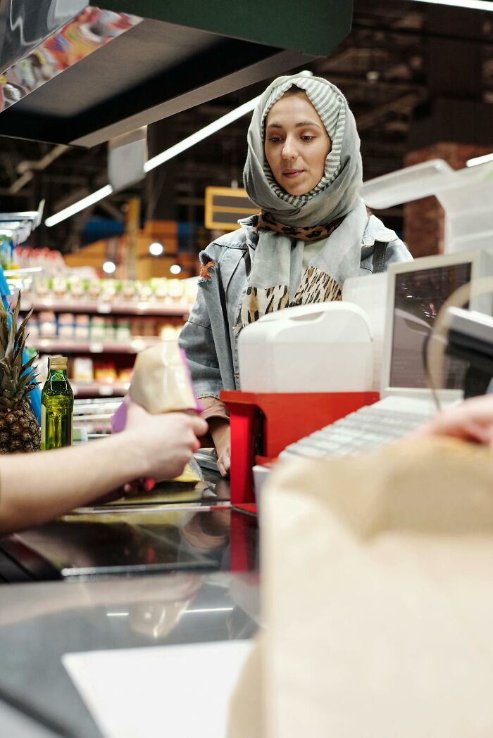 Woman at grocery store checkout counter holding items, illustrating moments people embarrassed themselves hilariously.