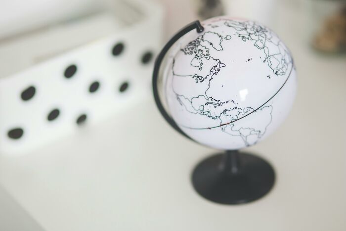 Small white globe with black country outlines on a stand, used to identify countries by marks on the world map.