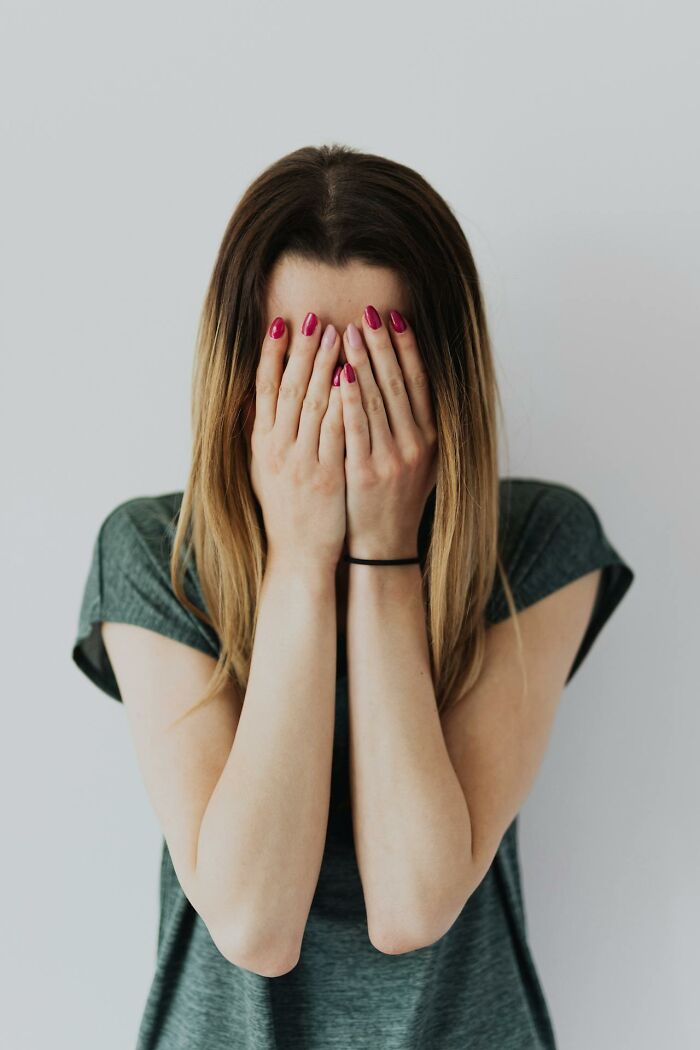 Young woman covering her face with hands, expressing emotion, illustrating online dating advice and experiences concept.