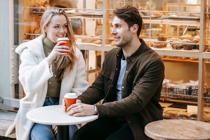 Couple enjoying coffee and conversation at a bakery, illustrating successful connections through online dating advice.