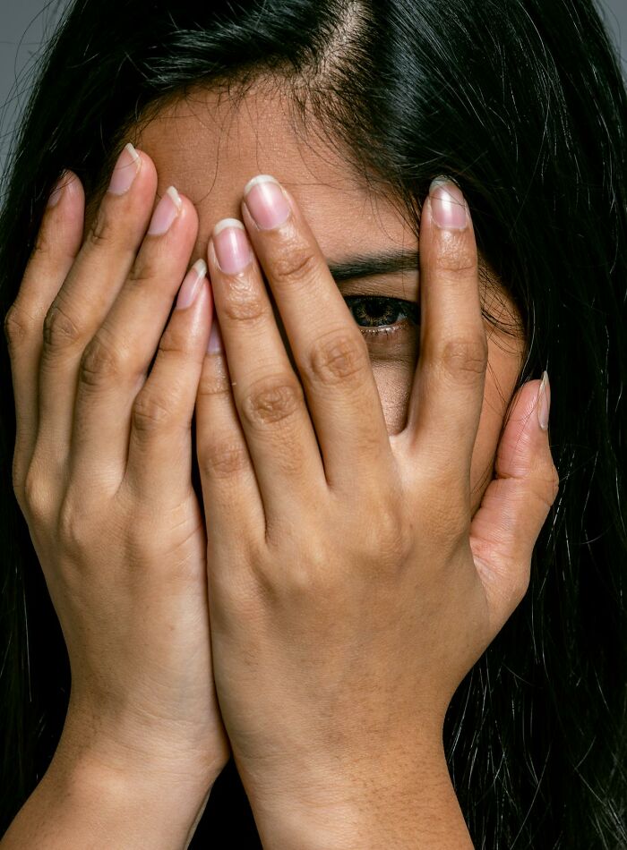 Woman hiding her face with hands, symbolizing secrets people are hiding from their partners and emotional concealment.