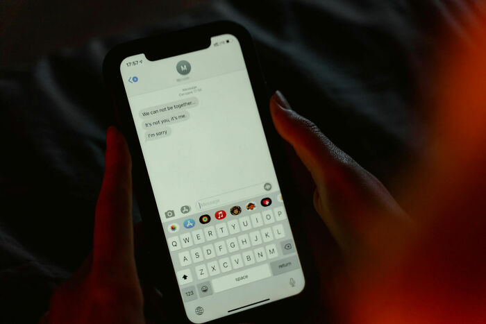 A person holding a phone showing a breakup text message, illustrating online dating experiences and advice.