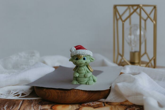 Small green figurine wearing a Santa hat on a wooden surface, symbolizing shocking and dark secrets that could ruin lives.