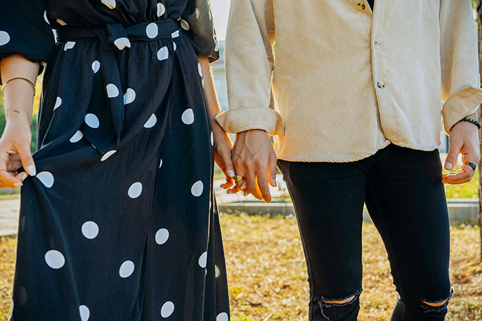 Couple holding hands outdoors with tension, illustrating man ruins marriage by stealing wife's tea set and giving it away.