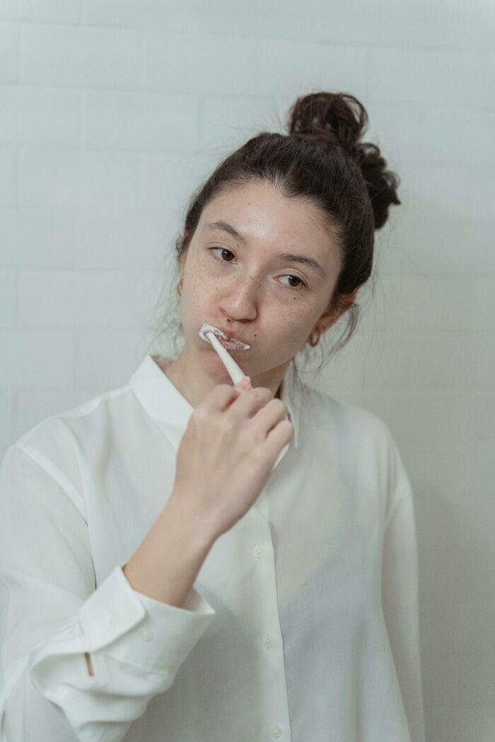 Young woman brushing teeth, representing secrets people are hiding from their partners in an everyday moment.