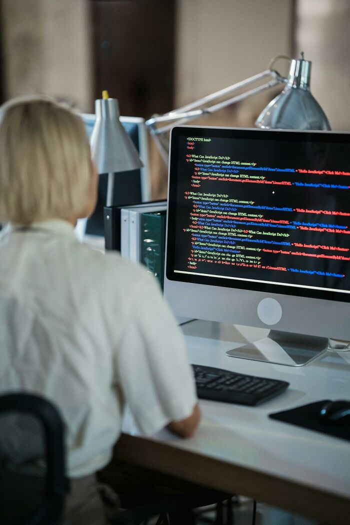 Person coding on a computer screen with HTML and JavaScript visible, highlighting subtle everyday sexism issues.