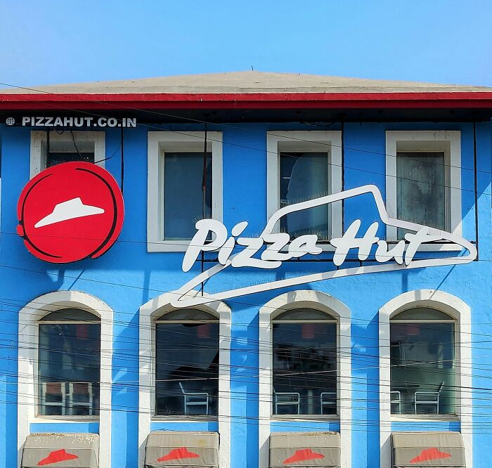 Blue building exterior with Pizza Hut logo and windows, relevant to stalking stories shared by women in a unique confessions article.