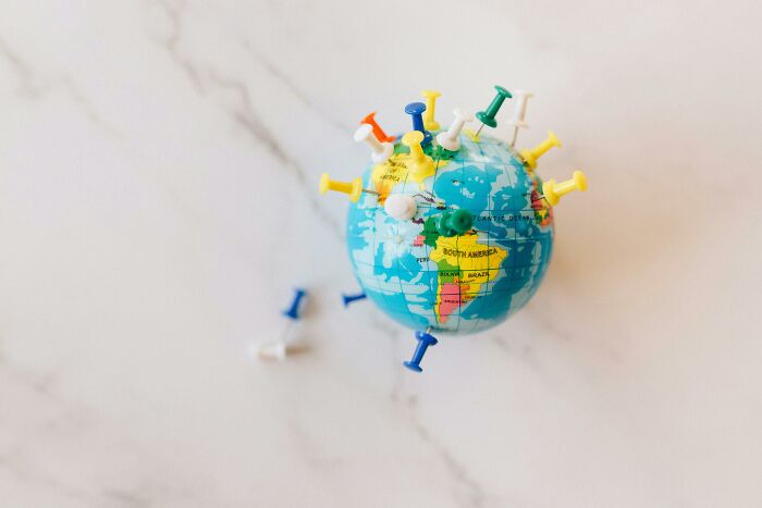 Small globe with colorful push pins marking various locations, illustrating a global geography challenge concept.