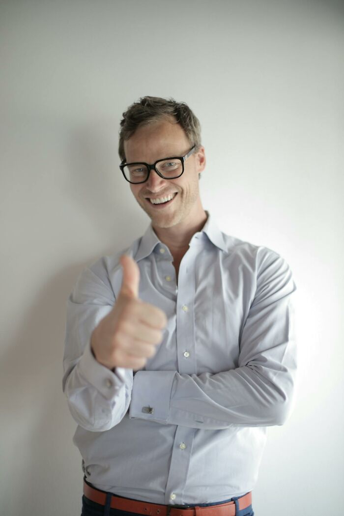 Smiling man wearing glasses and a light shirt giving thumbs up, illustrating moments when karma came instantly.