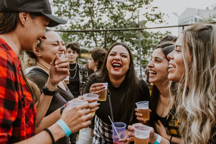 Group of friends laughing and holding drinks outdoors, illustrating social moments tied to disturbing things folks were told.