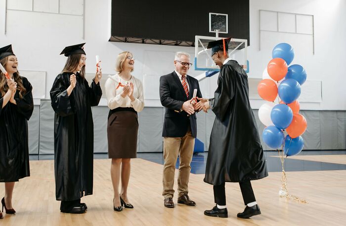 Graduates celebrating and receiving diplomas in a gym, illustrating women’s unhinged stalking stories for FBI SEO keyword.