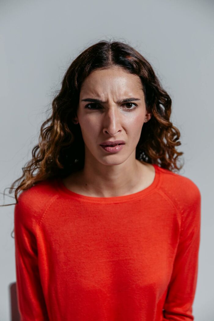 Woman in a red shirt with a confused and suspicious expression showing signs of someone having an affair.