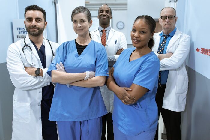 Diverse group of confident medical professionals in scrubs and lab coats, highlighting gender roles and subtle sexism issues.