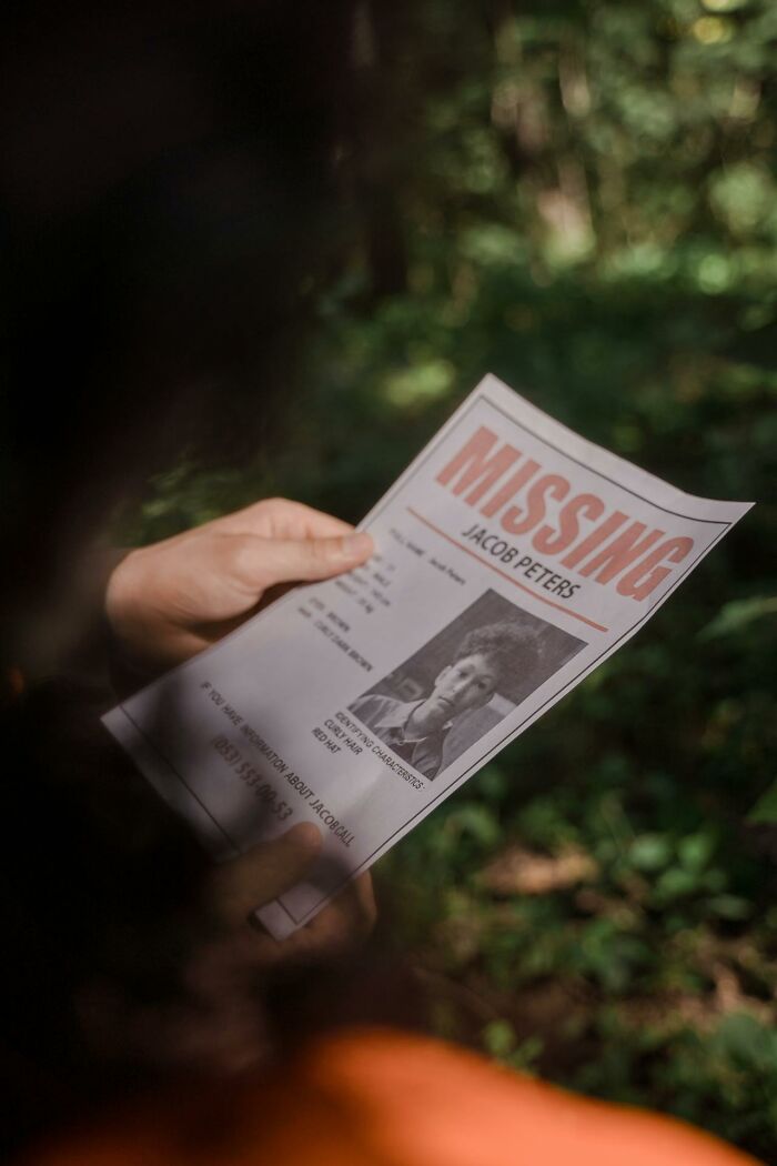 Person holding a missing person flyer outdoors, illustrating true crime fans' interest in unsolved cases.