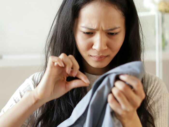 Woman closely inspecting a fabric with intense focus, illustrating attention to detail and investigation skills related to stalking.