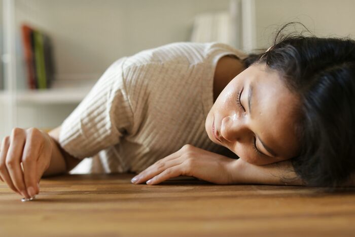 A woman resting her head on a wooden table, reflecting on chaotic and dramatic breakup stories.