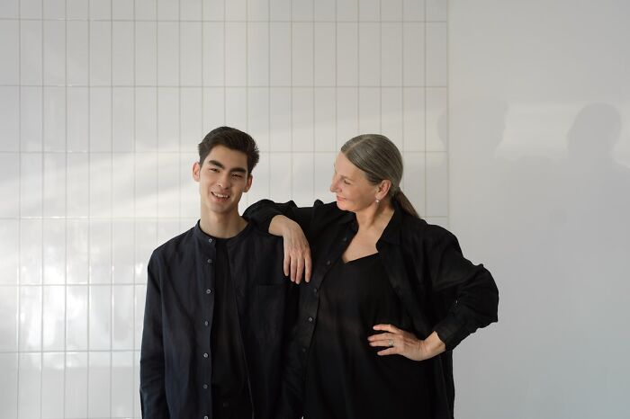 A smiling woman and man standing confidently against a white tiled wall representing secrets people hide from partners.