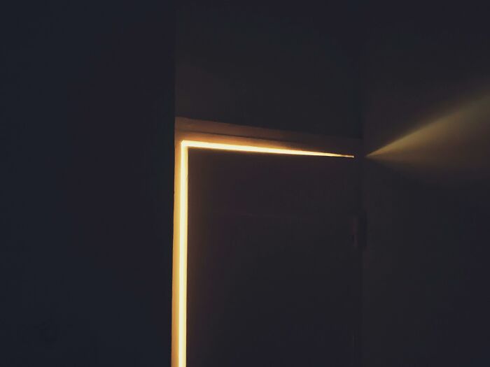 Dimly lit door slightly open with warm light shining through, symbolizing childhood rules and therapist reflection.