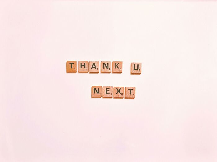 Wooden Scrabble tiles on a light background spelling thank u next, related to IQ and rebus quiz challenge concept.