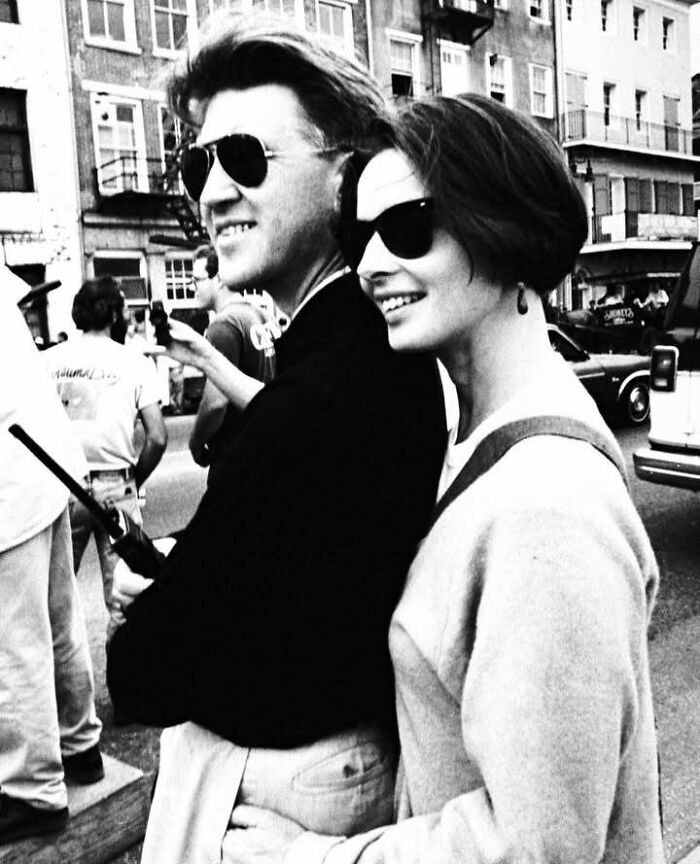 Couple wearing sunglasses smiling on city street, representing people who left a mark in the movie and music industries.