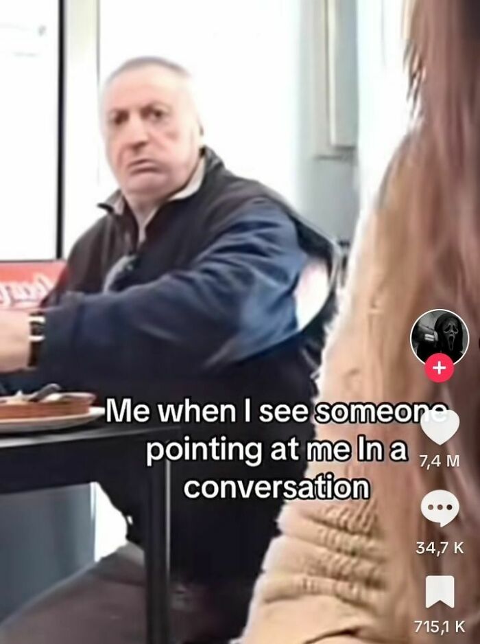 Man in a jacket with evil thoughts expression reacting to someone pointing at him during a conversation meme.
