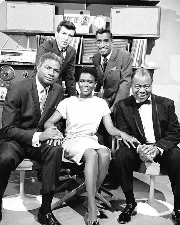 Black and white photo of iconic figures from the movie and music industries posing together in a studio setting.