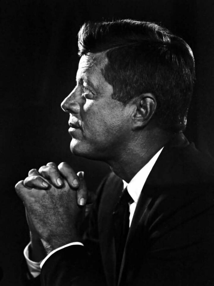 Black and white profile of a man in a suit with hands clasped, representing people who left a mark in movie and music industries.