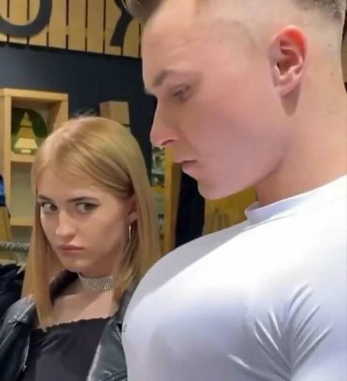 Young woman giving a suspicious look to a young man, capturing the vibe of evil thoughts in a casual indoor setting.