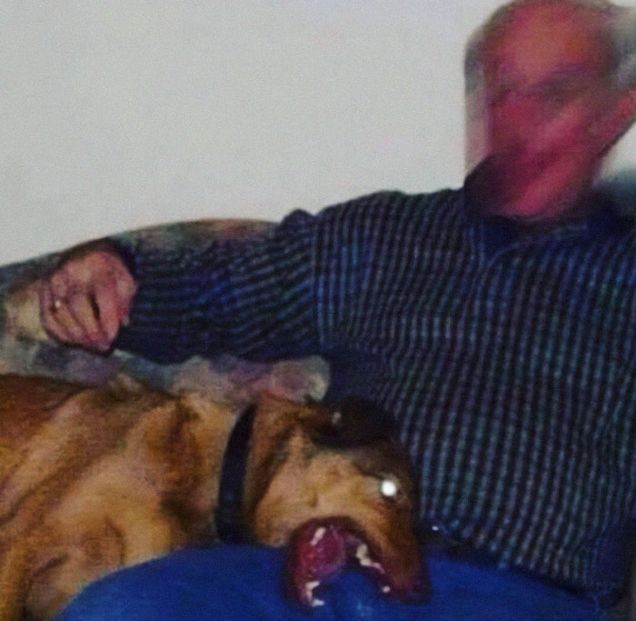 Man sitting on couch with dog, captured in hilarious photo just before disaster struck, showing chaotic moment with blurred face.