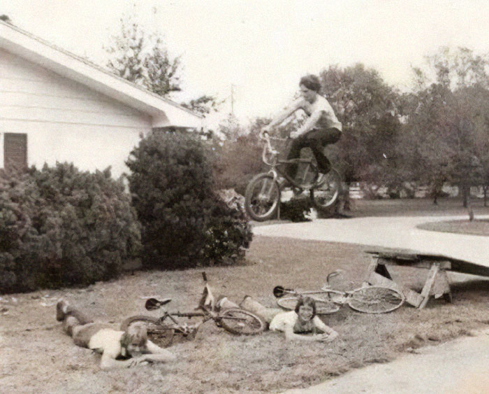 Boy on bike jumping over two kids lying on the ground in a hilarious photo taken before disaster struck outdoors.