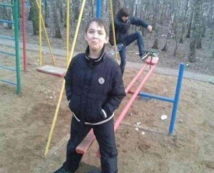 Two boys at a playground with one falling off a seesaw, a hilarious photo taken just before disaster struck.