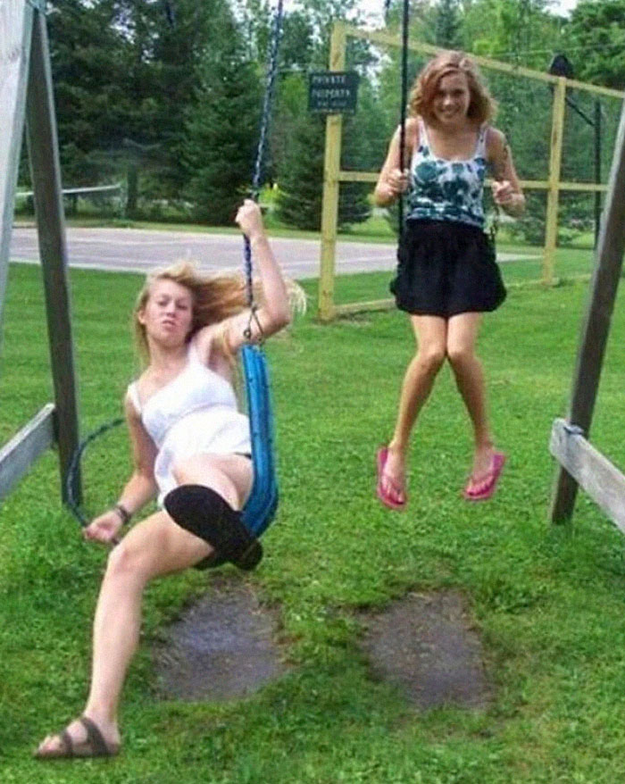 Two women on swings with one woman falling off, a hilarious photo captured just before disaster struck.