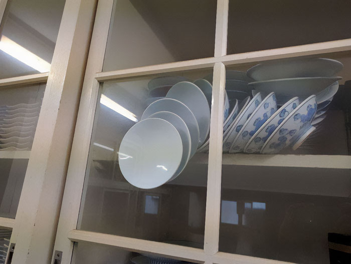 Dishes precariously stacked inside a cabinet, captured in a hilarious photo before disaster struck.