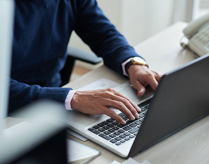 Person typing on laptop at desk, representing educated individual involved in scam investment and financial trouble. Person typing on laptop at desk, representing educated individual involved in scam investment and financial trouble.