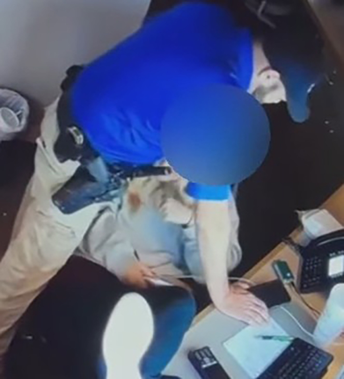 Police chief leans over 18-year-old dispatcher in office setting during disturbing leaked video moment.