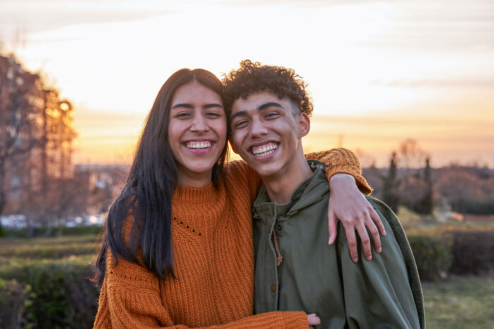 Two friends smiling outdoors at sunset, showcasing tattoo artists messed up moments with visible tattoos.