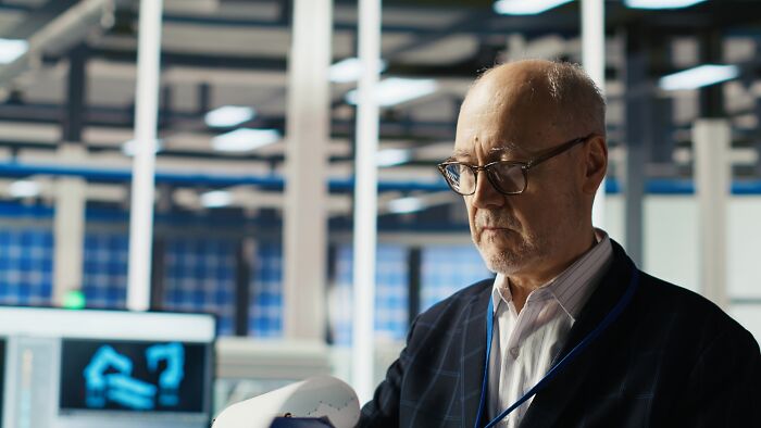 Older man examining documents in a modern office, illustrating people sharing potentially dangerous situations at work.