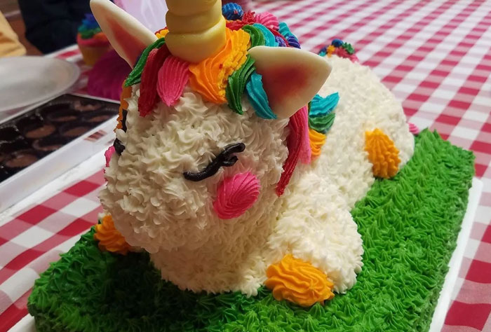 Unicorn cake with colorful icing details on a green frosting base, showcasing creative bakery cake decoration.