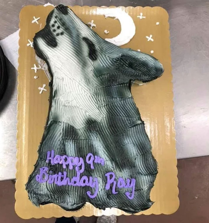 Wolf-shaped cake with icing details and purple birthday message, showcasing the perfect delicious icing on the cake.