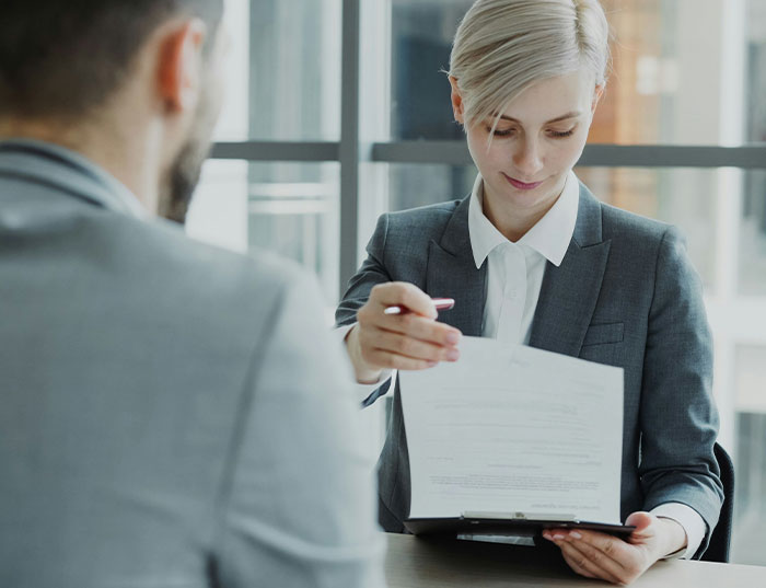Woman in business attire holding documents during a meeting, illustrating woman takes revenge on bakery manager.