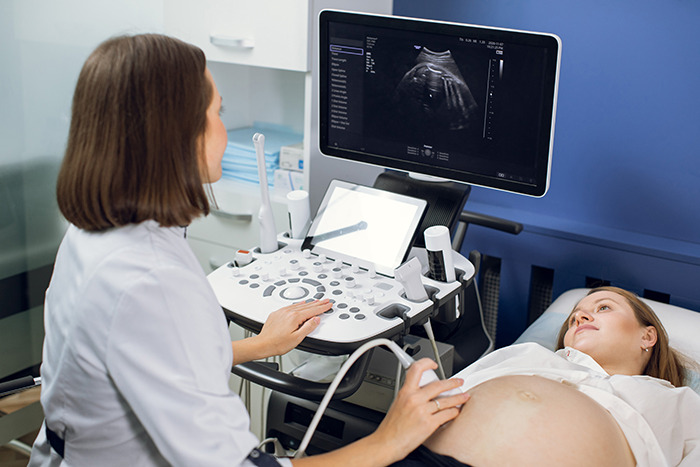 Pregnant woman undergoing an ultrasound sonogram as a doctor examines the sonogram image on the monitor.